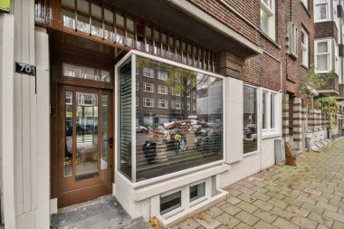 Amsterdam, Hollanda - 10 Nisan 2021: Penceresinde insanlar olan bir bina ve caddenin diğer tarafında park edilmiş araçlar, dışarıdan görüldüğü gibi.