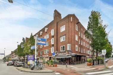 Amsterdam, Hollanda - 10 Nisan 2021: kaldırıma parketmiş bisikletli ve sokakta yürüyen insanlar olan bir tuğla bina