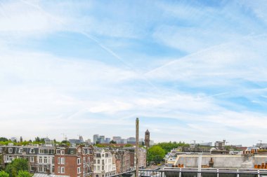 Amsterdam, Hollanda - 10 Nisan 2021: Açık mavi gökyüzü gününde yüksek açılı binalar ve ağaçlarla çevrili bir şehir alanı
