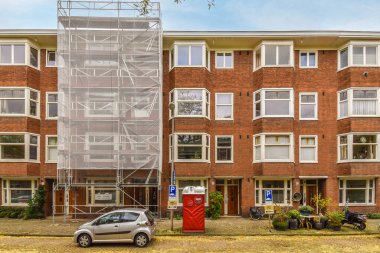 Amsterdam, Hollanda - 10 Nisan 2021: Önünde yangın söndürücü olan bir apartman ve yanında iki araba park edilmiş.