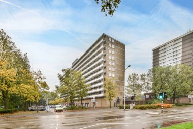 Amsterdam, Hollanda - 10 Nisan 2021: Önünde binalar ve ağaçlar olan bir şehir caddesi, yağmurlu bir günde bir kavşaktan görüldüğü gibi.