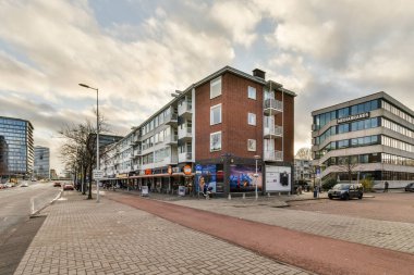 Amsterdam, Hollanda - 10 Nisan 2021: Yol kenarına park edilmiş bina ve arabalarla dolu bir şehir caddesi, bir ofis binasının önünde.