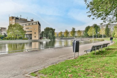 Amsterdam, Hollanda - 10 Nisan 2021: Nehir kıyısı fotoğrafının diğer tarafındaki bir su ve binaların önünde boş bir bank