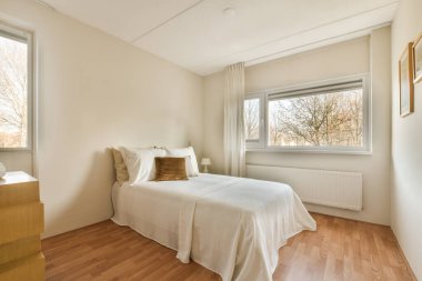 Odanın ortasında bir yatak odası, ahşap döşemeleri ve beyaz duvarları olan büyük bir pencere.