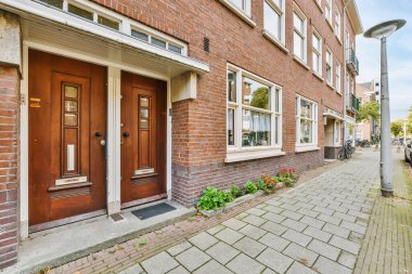 Amsterdam, Hollanda - 10 Nisan 2021: Ön kapıda beyaz süslemeli kırmızı tuğla bir bina ve fotoğraftaki iki pencere sokaktan çekildi