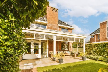 Bahçenin bahçesinde yeşil çimenler ve ağaçlar olan bir evin dışında.