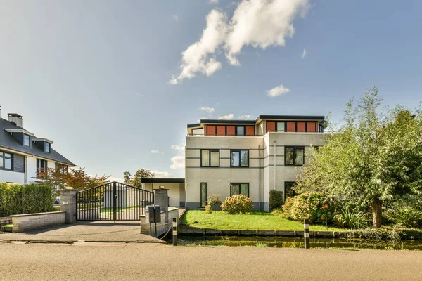 stock image a house in the middle of an urban neighborhood with trees, shrubs and bushes on either side of the road