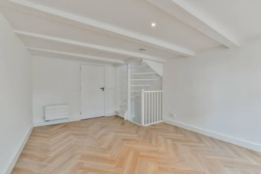 Beyaz duvarları ve ahşap döşemeleri olan boş bir oda. Köşesinde bir radikal var.