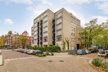 Amsterdam, Hollanda - 10 Nisan 2021: Kenarında arabalar ve fotoğrafın ortasında binalar olan bir şehir caddesi, sokağın karşısından çekildi.