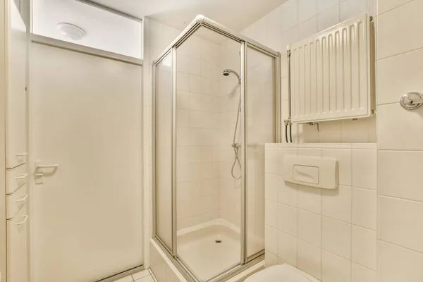 壁の浴槽の横の角にシャワーストールとトイレのあるバスルームは白いタイルです — ストック写真