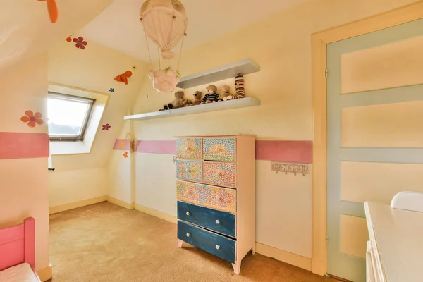 stock image a childs room with pink and blue accents on the walls, white cupboards, and ceiling lights