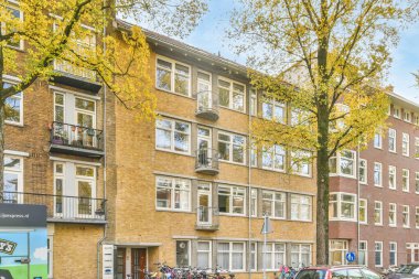 Amsterdam, Hollanda - 10 Nisan 2021: Hollanda 'da bir apartman kompleksi, bisikletleri sokağa park edilmiş ve arabalar kaldırımlı yol boyunca park edilmiş.