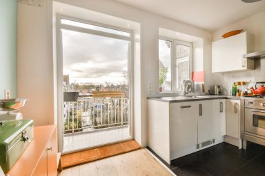 Bahçe alanına açılan açık kapısı olan küçük bir mutfak ve içinde yemek pişirmek veya dinlenmek için açık bir alan.