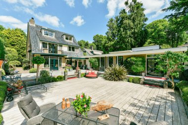 Amsterdam, Hollanda - 10 Nisan 2021: Bahçesinde veranda mobilyası ve ağaçları olan, yemyeşil yapraklarla çevrili bir ev