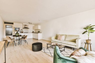 Odanın ortasında beyaz duvarları ve ahşap döşemeleri olan bir oturma odası, yeşil bir kanepe var.