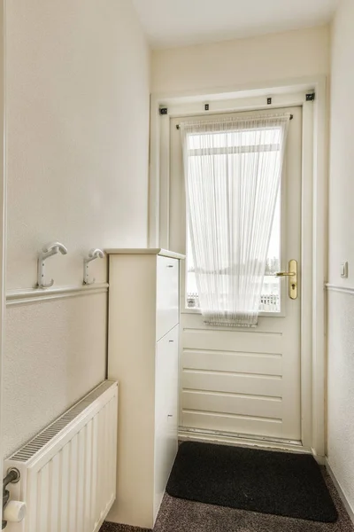 a door and window in a small room with white trim on the walls, carpeted floor and radiaing