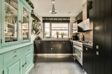 Merkezinde siyah dolaplar ve beyaz aletler olan bir mutfak ve verandaya açılan açık bir kapı.