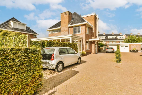 stock image a house with a car parked in the driveway and two cars parked on either side of the driveway there is a blue sky