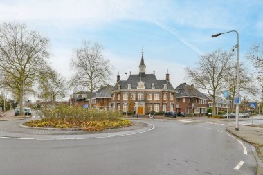 Amsterdam, Hollanda - 10 Nisan 2021: ortasında bir kilise ve her iki tarafında ağaçlar olan bir sokak köşesi, diğer tarafında park edilmiş bazı arabalar