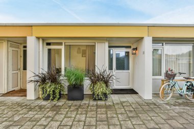 Amsterdam, Hollanda - 10 Nisan 2021: Giriş kapısının yanında saksıları ve bitkileri olan bir evin önüne park edilmiş bir bisiklet