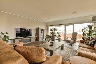 Odanın ortasında kanepeleri ve düz ekran televizyonu olan bir oturma odası duvarda gösteriliyor.