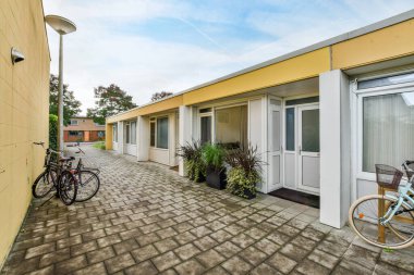 Amsterdam, Hollanda - 10 Nisan 2021: Her iki tarafında kapı ve pencereler olan bir binanın önüne park edilmiş bisiklet, duvara yaslanmış bir bisikletin yanında.
