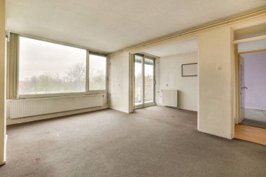 Odada tek bir kişi bile olmadan boş bir oturma odası ve başka bir odaya açılan iki kapı var.