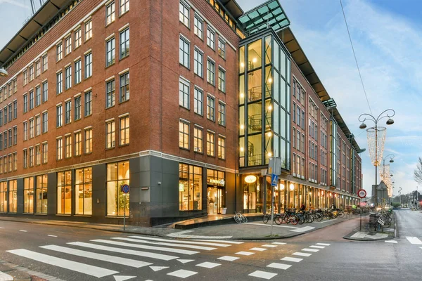 stock image a city street with buildings and people walking on the crosswalk at an intersection in front of a red brick building