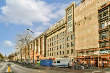 Binalar ve bisikletli insanlarla dolu bir şehir caddesi. Caddenin ortasında yoldan geçen bir otobüs var.