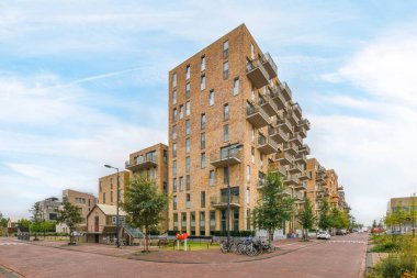 Amsterdam, Hollanda - 10 Nisan 2021: En üst katında birçok pencere ve balya bulunan tuğla bir bina, önünde park edilmiş bir bisiklet var.