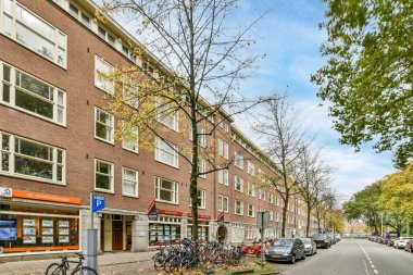 Bisikletleri yolun kenarına park etmiş kırmızı tuğlalı bir apartmanın önünde.