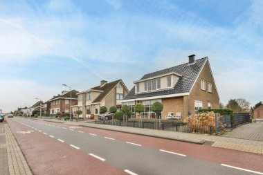 Amsterdam, Hollanda - 10 Nisan 2021: Arka planda evler ve yan tarafında park edilmiş bir araba olan boş bir cadde