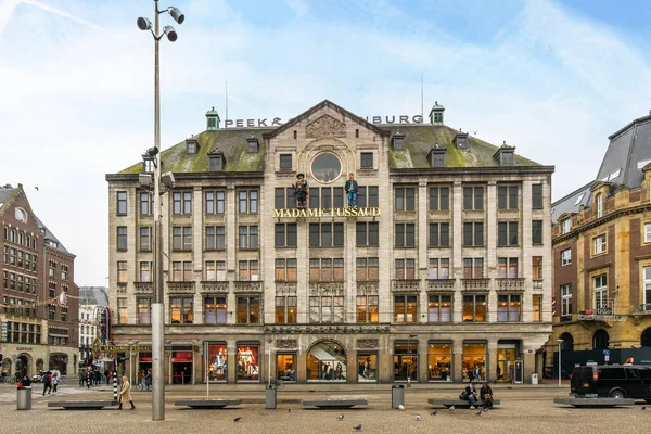 stock image Amsterdam, Netherlands - 10 April, 2021: a large building in the middle of a city with people walking around it and cars parked on the street below