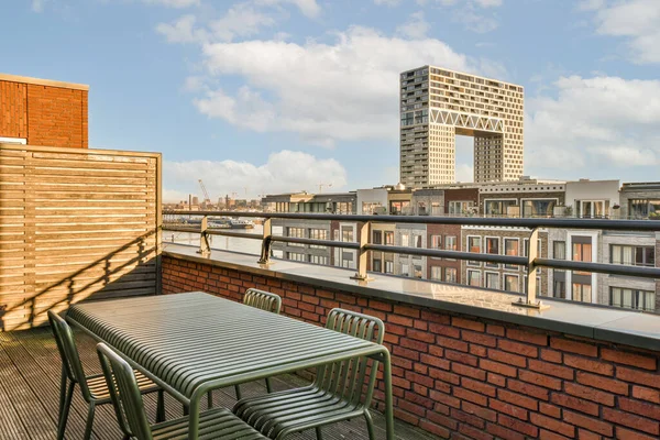 一张前置有椅子和桌子的阳台是在一座公寓楼的屋顶平台上拍摄的 — 图库照片