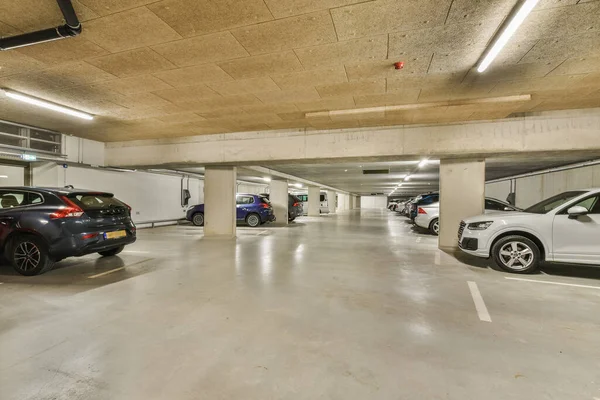 stock image Amsterdam, Netherlands - 10 April, 2021: an underground parking area with cars parked in the garages and people walking through the space to get their rides