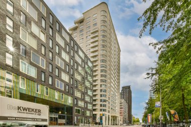 Yolun kenarına park etmiş arabalarla dolu bir şehir caddesi. Hemen yanındaki apartmanın önünde.