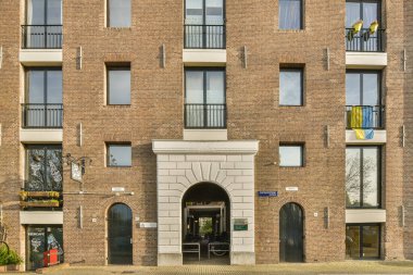 Amsterdam, Hollanda - 10 Nisan 2021: En üst katında birçok pencere ve balya bulunan tuğla bir bina, önünde bir yangın hidratörü var.