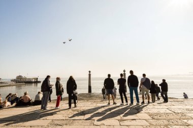 Sudaki insanlar gökyüzünde uçan bir kuşla berrak mavi gökyüzünde parlayan güneşle