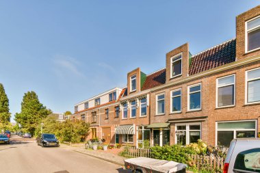 Arabaların yan tarafında park edilmiş bir cadde ve arka planda evleri olan, arabaların perspektifinden alınan bir sokak.