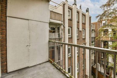 Balkon korkulukları ve her iki tarafında balkon ve balkon olan bir apartmanın dışında sokağa bakıyor.