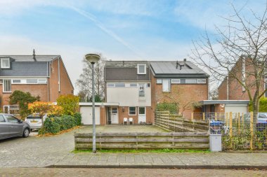 Amsterdam, Hollanda - 10 Nisan 2021: Garaj yoluna park edilmiş bazı evler ve iki katlı evin yanına park edilmiş bir araba