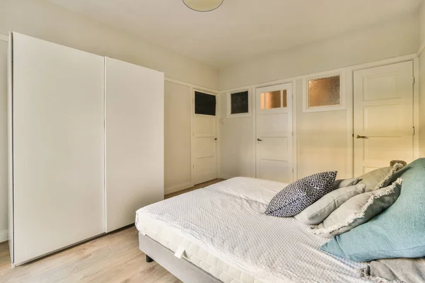 他の部屋のドアの前の壁にベッドと白い食器棚のあるベッドルーム — ストック写真