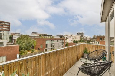 Amsterdam, Hollanda - 10 Nisan 2021: Dışında sandalyeler ve masalar olan bir balkon, arka planda şehir manzarasına bakıyor