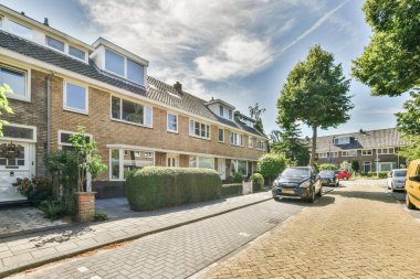 Amsterdam, Hollanda - 10 Nisan 2021: yan tarafında arabalar ve arka tarafında evler olan bir cadde, hepsi birbirine bakıyor.