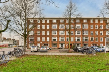 Önünde ve yanındaki kaldırımda bisikletleri olan tuğladan bir apartman dairesi mavi bir gökyüzü.