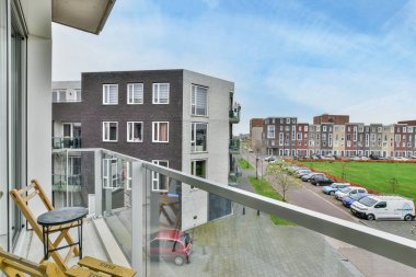 Amsterdam, Hollanda - 10 Nisan 2021: Sokakta arabaların park ettiği bir balkon ve uzaktaki evlerin dışarı bakan bir apartman penceresinden alındığı