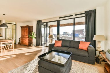 Odanın ortasında kanepeleri, kahve masası ve yemek odası olan bir oturma odası geniş pencereli.