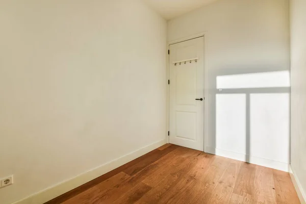 房间的右边是一个有白色墙壁和木地板的空房间 左边有一扇门 — 图库照片