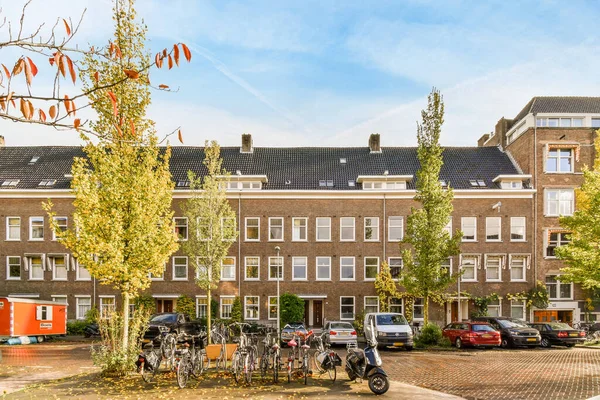 Amsterdam, Hollanda - 10 Nisan 2021: Yolun her iki yanında bisikletleri ve ağaçları olan bir apartman kompleksi, bazı binalar görünür.