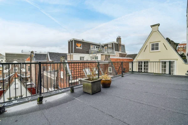 stock image a rooftop with some buildings in the background and blue skies overhead over the roofs are white, red and yellow